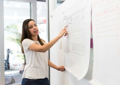 woman standing pointing paper on board