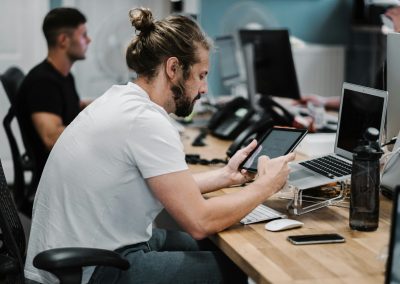 man holding turned-on iPad in front of turned-off MacBook Air