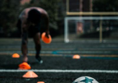 black short coated dog playing soccer ball on black asphalt road during daytime