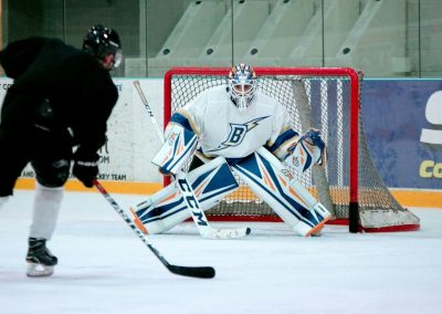 man taking aim for goal on hockey goalie